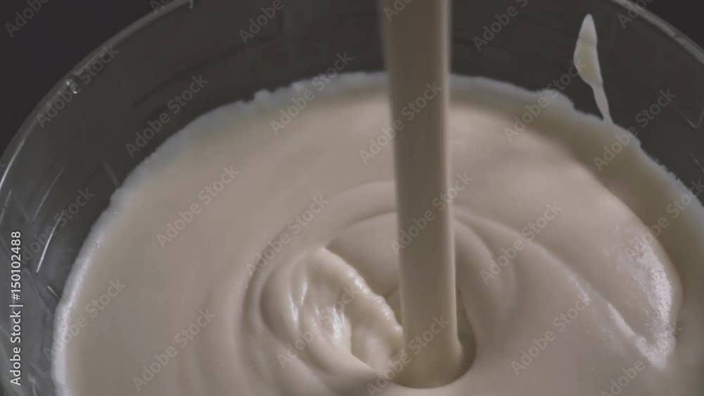 The batter in the bowl is poured into a measuring spoon. Slow mo The batter in the bowl is poured into a measuring spoon. Slow mo