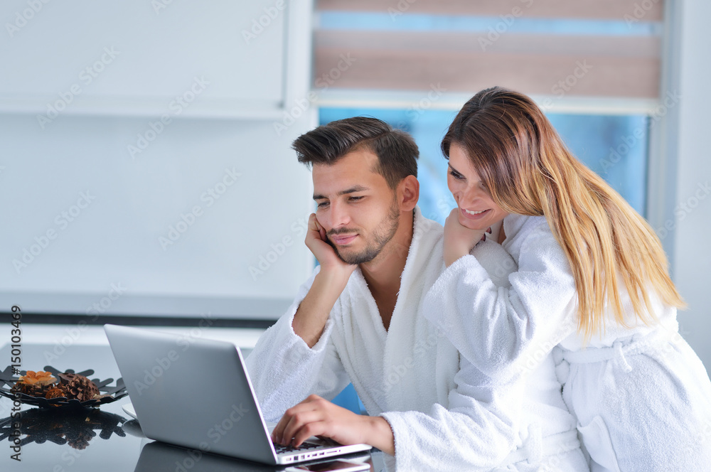 Portrait of a couple in the kitchen and using a laptop Portrait of a couple in the kitchen and using a laptop