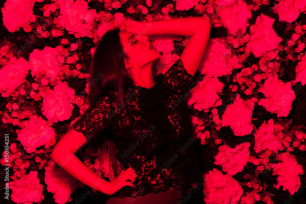 Sexy woman posing in red light on flower background. Sexuality and sensuality concept