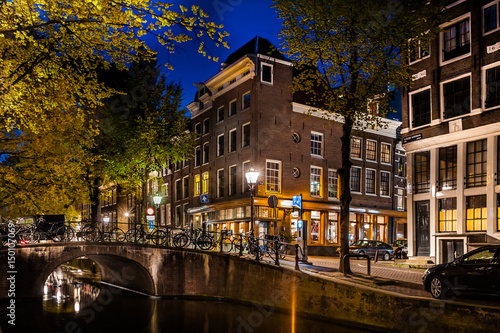 Night shot of Amsterdam canal city view with bicycles on the bridge, Netherlands