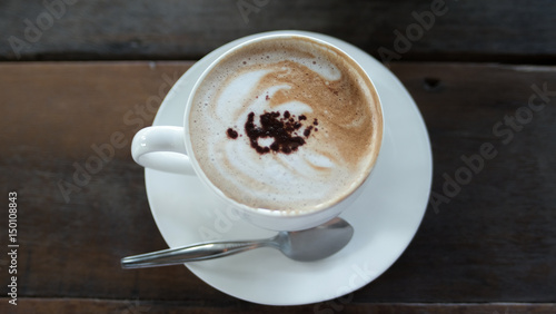 Fényképezés Hot mocca cofee in a cup with spoon and white dish, placed on wooden table