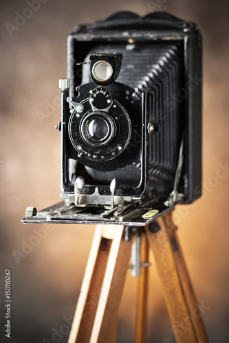 Old camera on a tripod on an old background close-up