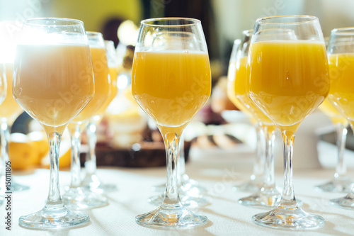 Glasses with tasty fresh orange fruit juice on summer wedding greeting