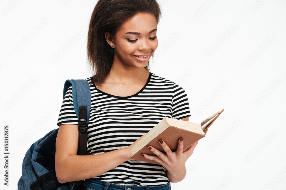 Smiling afro american teenager girl with backpack reading book Smiling afro american teenager girl with backpack reading book