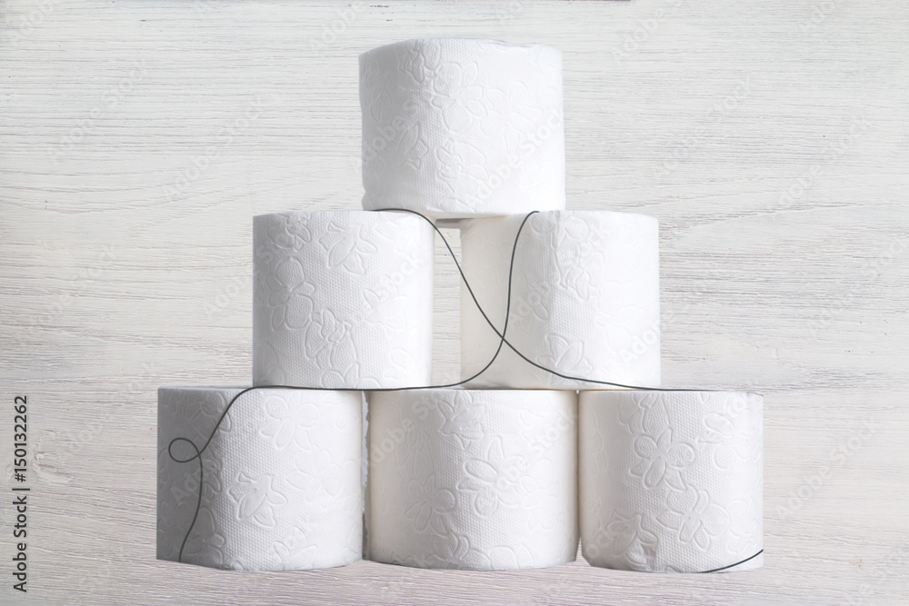 Stack of toilet paper rolls on wooden table against white brick wall. Copy space. Stack of toilet paper rolls on wooden table against white brick wall. Copy space.