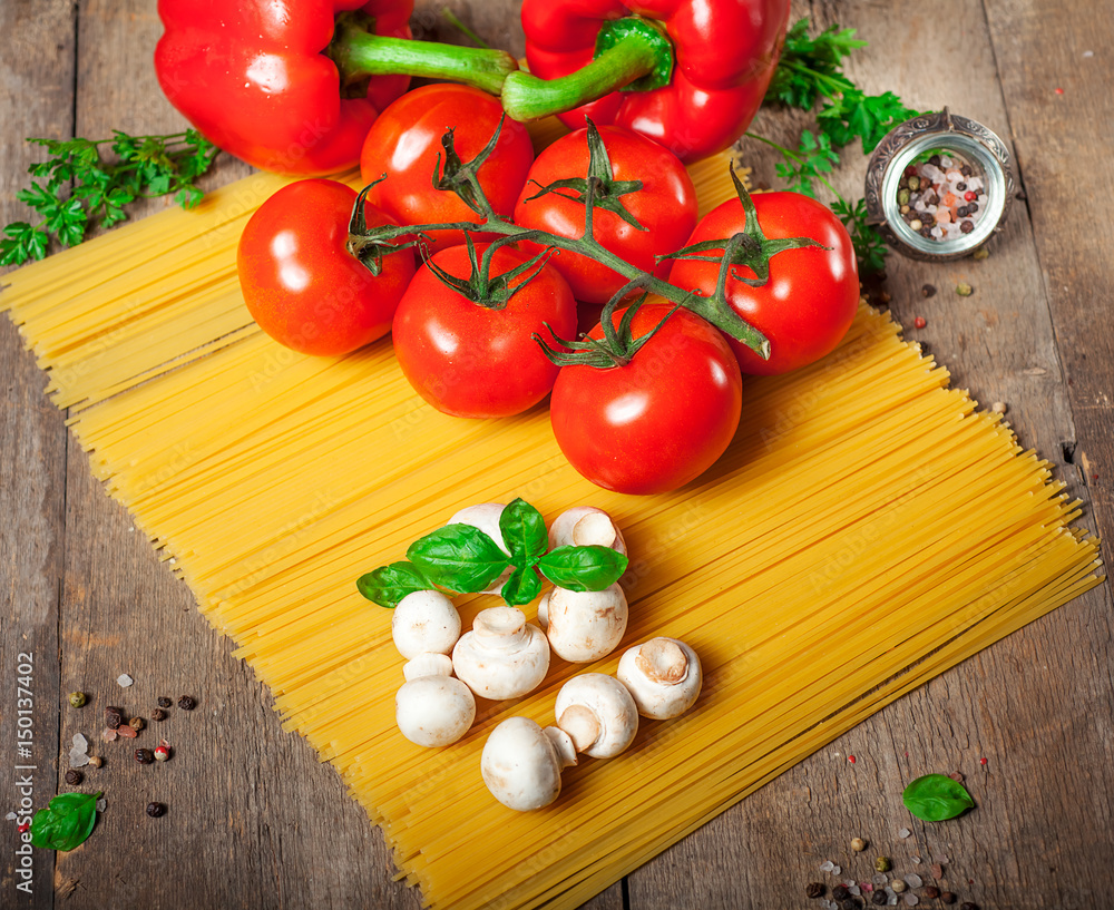 Italian dry pasta spaghetti with tomatoes and fresh herbs on a dark wooden background, selective focus Italian dry pasta spaghetti with tomatoes and fresh herbs on a dark wooden background, selective focus