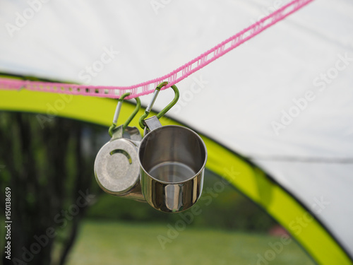 キャンプ場のタープとコップ　Tumblers hung under a tarp in a camping field photo