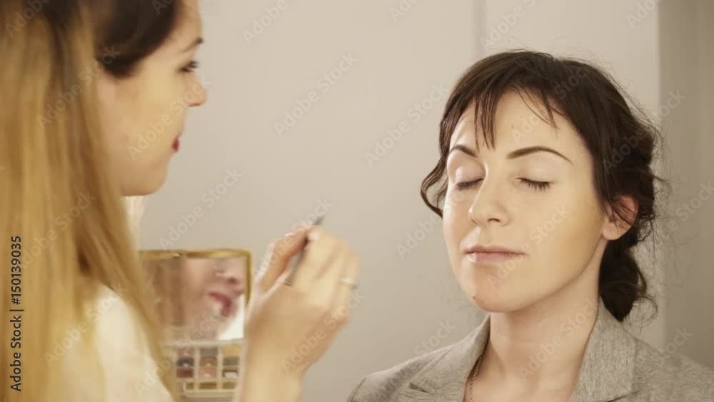 Makeup artist creating makeup for a young woman Makeup artist creating makeup for a young woman