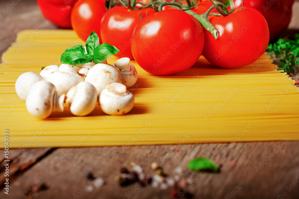Italian dry pasta spaghetti with tomatoes and fresh herbs on a dark wooden background, selective focus Italian dry pasta spaghetti with tomatoes and fresh herbs on a dark wooden background, selective focus