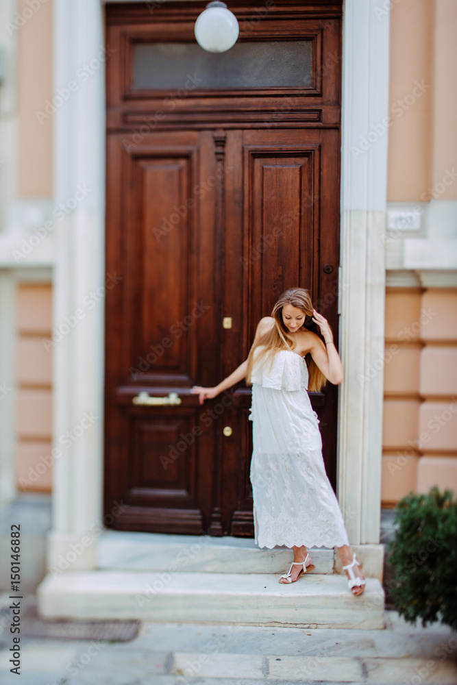 Fototapeta premium Woman in white dress in front of huge brown wooden door
