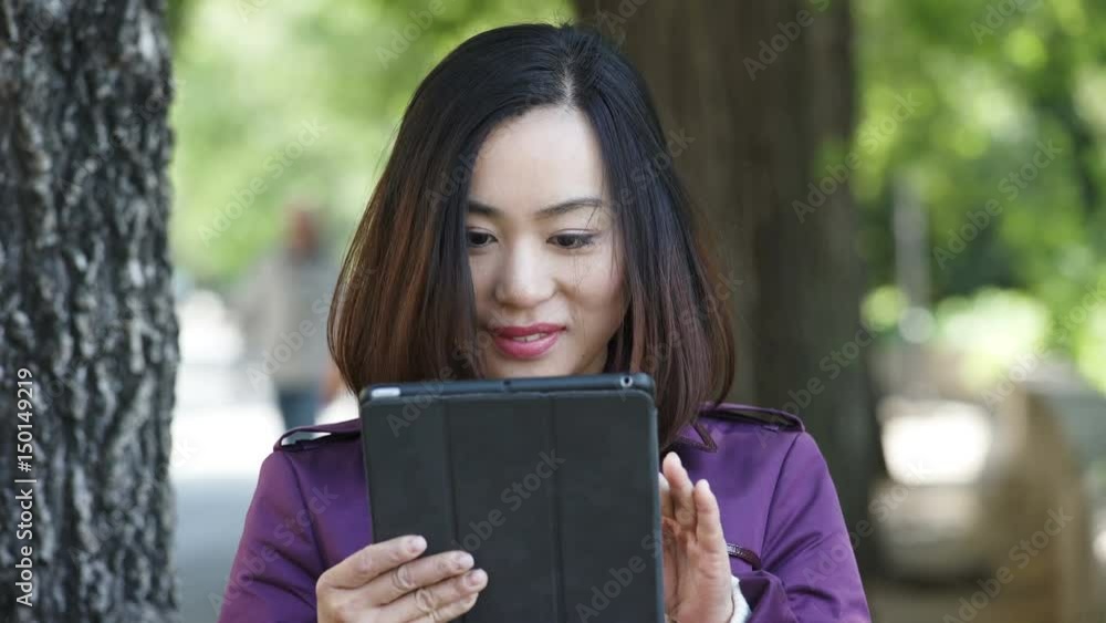 Asian young Woman Using Digital Tablet And Smiling- outdoor Asian young Woman Using Digital Tablet And Smiling- outdoor