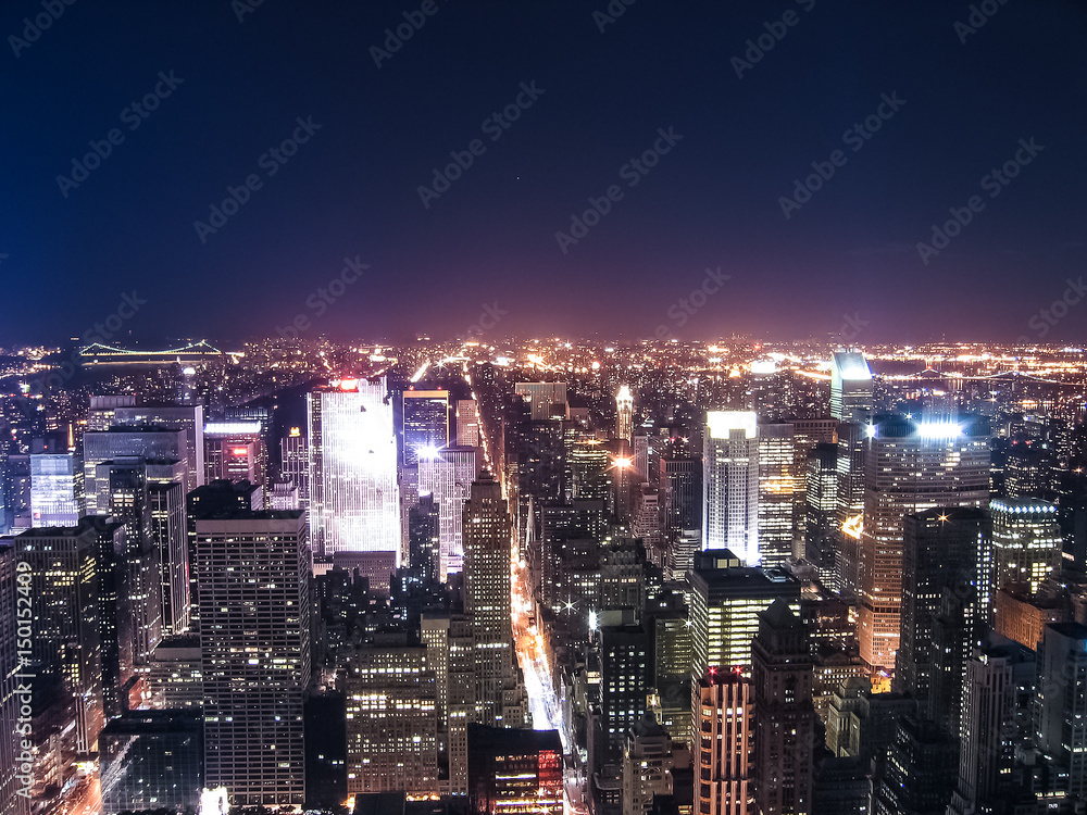 View of night cityscape or skyline of New York City with moon and illuminated buildings from Empire State Building