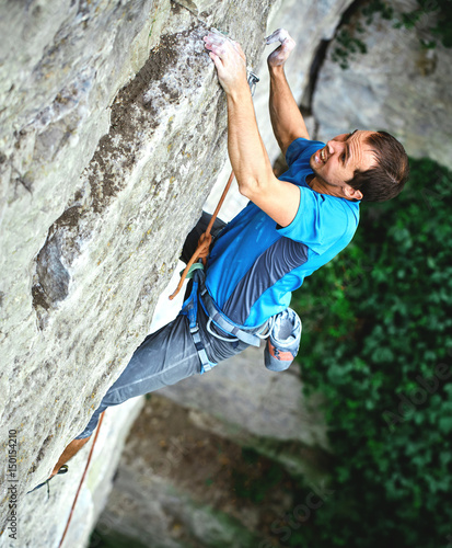 male rock climber. rock climber climbs on a rocky wall. man makes hard move