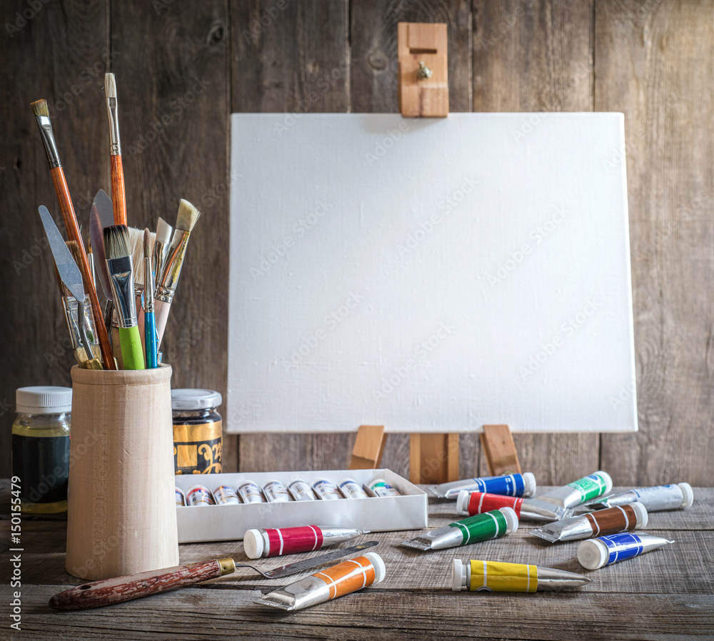 Fototapeta premium Artist's workshop. Canvas, paint, brushes, palette knife lying on the table.