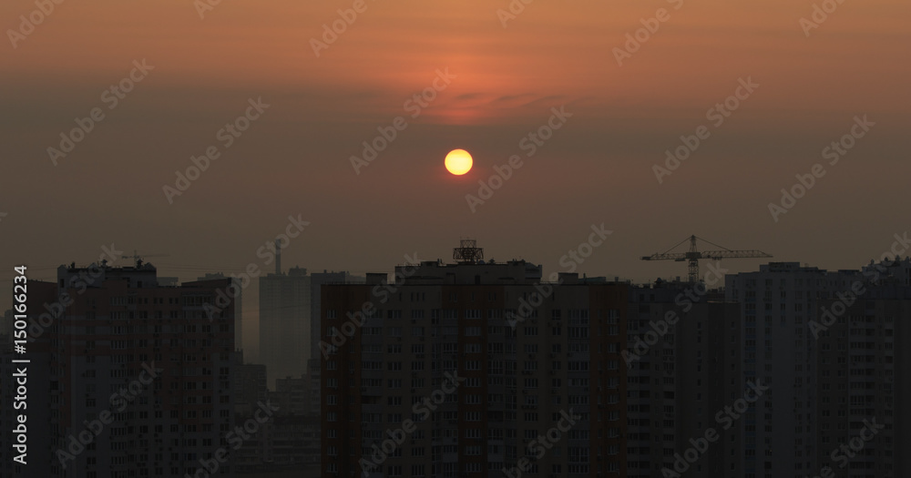 City sunset with a Sun disc in the middle of a red sky with appartment houses
