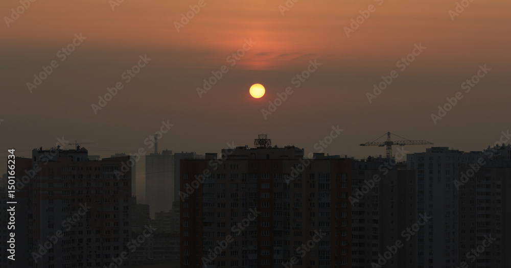 City sunset with a Sun disc in the middle of a red sky with appartment houses City sunset with a Sun disc in the middle of a red sky with appartment houses