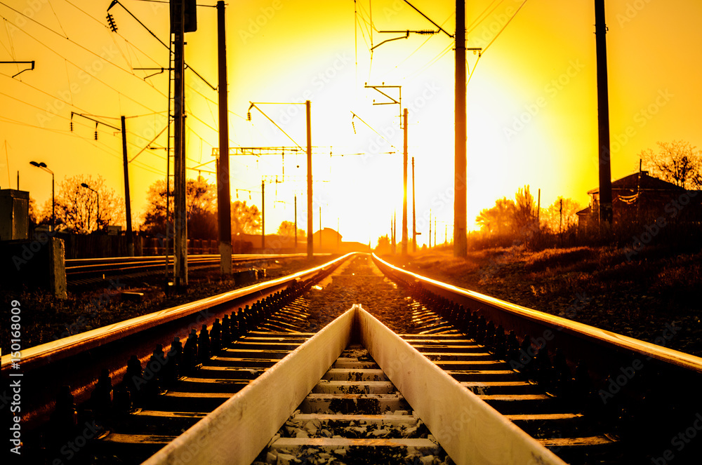 Railway - Railroad at sunset with sun, Rails and electric lines in yellow light