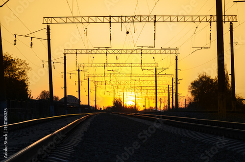 Railway - Railroad at sunset with sun, Rails and electric lines in yellow light