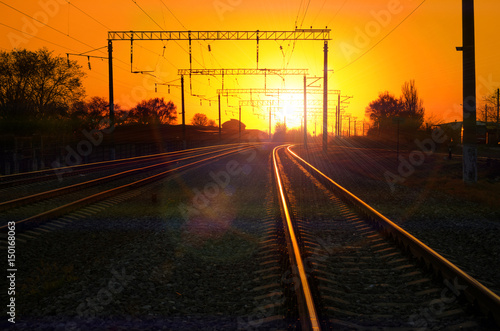 Railway - Railroad at sunset with sun, Rails and electric lines in yellow light