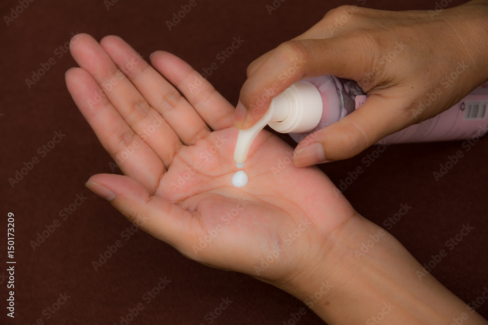 Hand of female holding sunscreen and squeeze into hand Hand of female holding sunscreen and squeeze into hand
