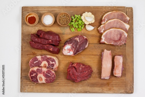 Varieties of meat with spices on wooden board