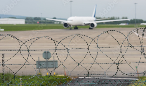 Photography airport security mesh and razor wire perimeter fence with jet airliner on the ru