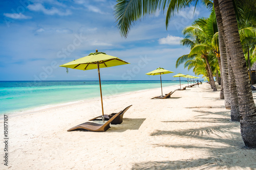 Fototapeta Naklejka Na Ścianę i Meble -  Tropical beach background at Panglao Bohol island with Beach chairs on the white sand beach with blue sky and palm trees. Travel Vacation