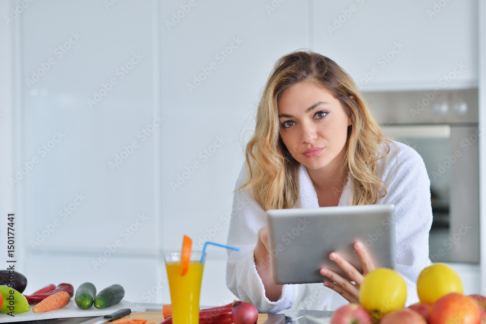 beautiful young woman using a digital tablet in the kitchen beautiful young woman using a digital tablet in the kitchen