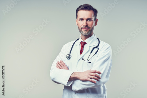 Canvas-taulu Portrait of handsome doctor standing with crossed arms. Isolated