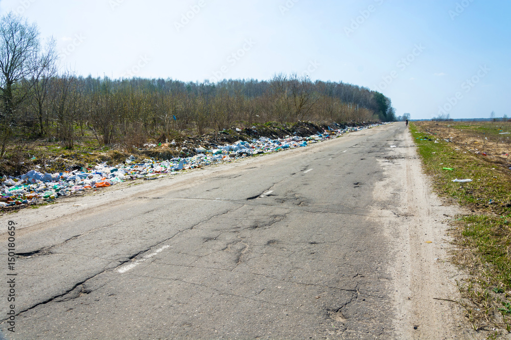 Piles of garbage along the bad asphalt road, Russia.