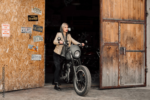woman pulls her bike. Motorcycle in the garage. A woman in a leather jacket. Motorcycle