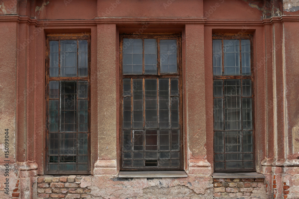 Old building facade with window. Facade of old abandoned building with three large windows. Old building facade with window. Facade of old abandoned building with three large windows.