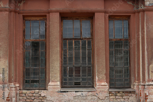 Old building facade with window. Facade of old abandoned building with three large windows.