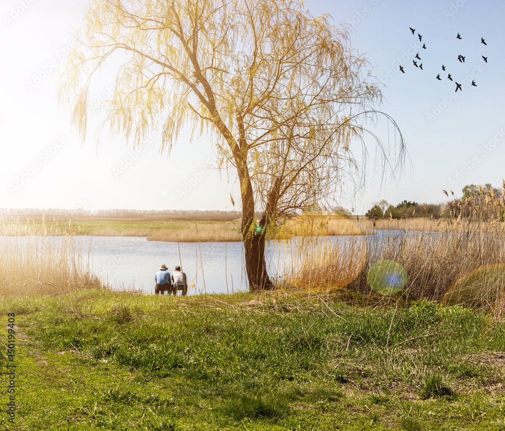 Obraz premium men sitting on the shore of the lake