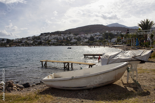 View of empty beach, small piers and white small boat at Turkbuku village in Bodrum peninsula in autumn. The image also shows how tourism crises effects the region.