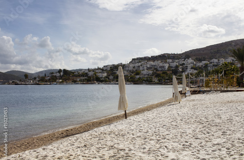 View of empty beach  closed sun shades  umbrellas   white summer houses and landscape in Turkbuku village on Bodrum peninsula in autumn. The image also shows how tourism crises effects the region.