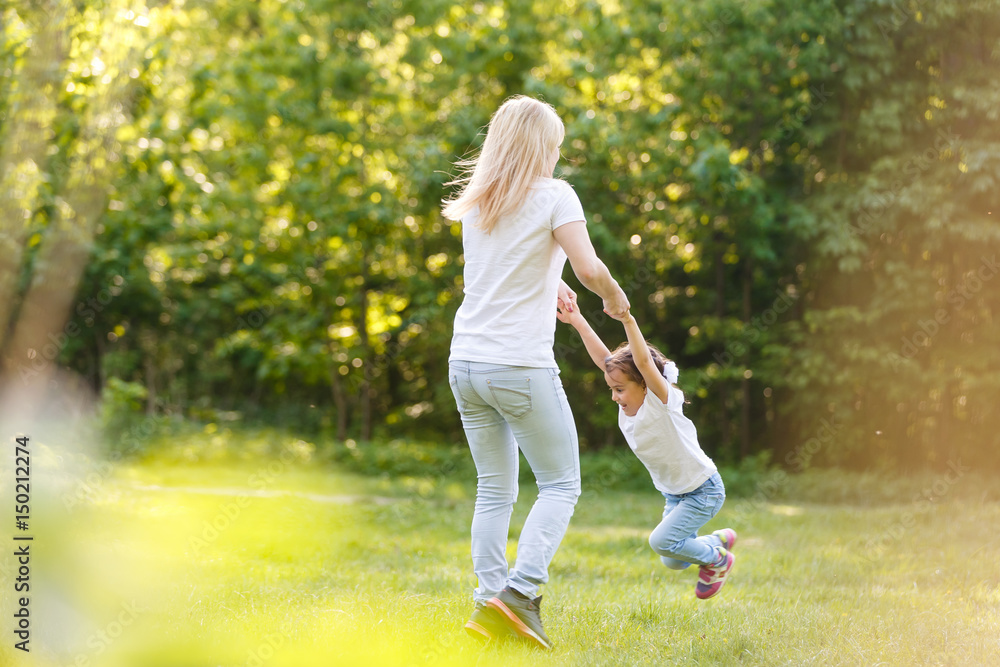 Mother and daughter playing circling around at the park on beautiful morning. Mother and daughter playing circling around at the park on beautiful morning.