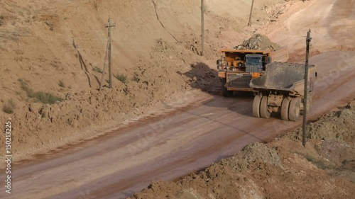 Mid shot of heavy mining trucks carring cargo in opencast mining quarry in sunny summer day. Bouxite mining quarry.