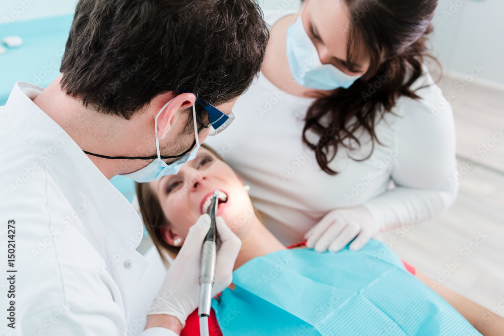 Dentist and assistant treating woman in clinic Dentist and assistant treating woman in clinic
