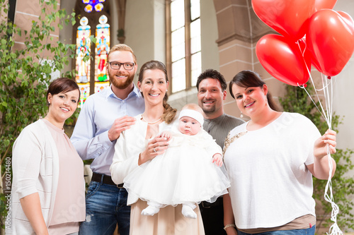 Familie mit Baby nach der Taufe vor dem Altar mit roten Luftballons photo