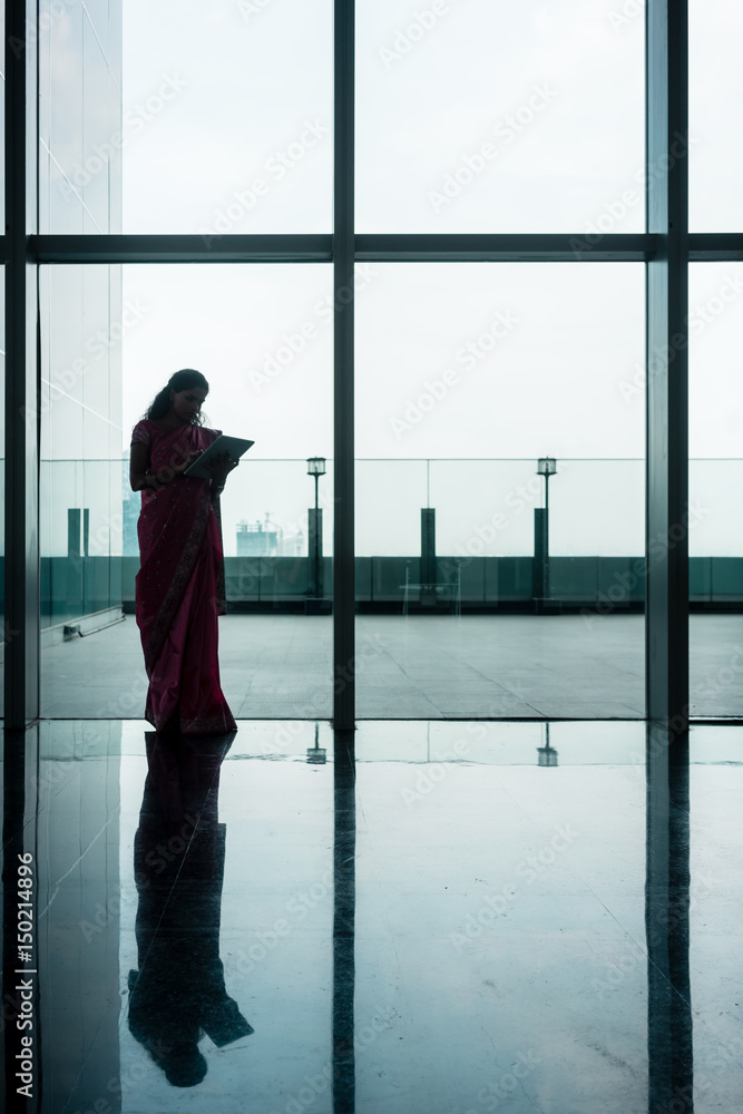 Indian woman using tablet on corridor of modern corporate building Indian woman using tablet on corridor of modern corporate building
