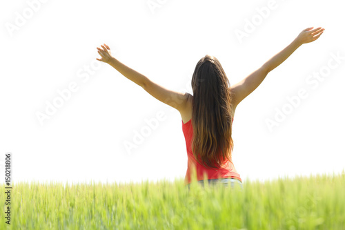 Happy woman raising arms in a field