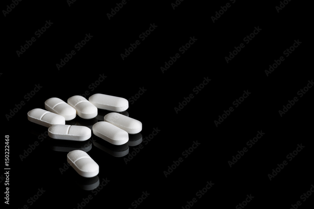 White pills on the black background