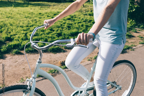 Slim girl in jeans and t-shirt sitting on the blue cruise bike on a sunny morning