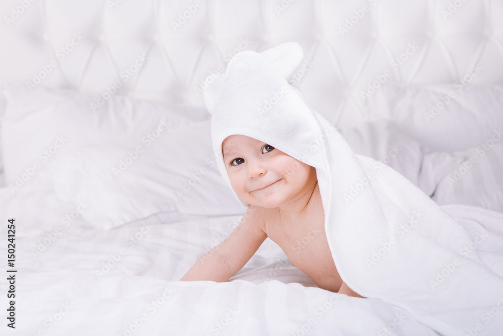 Adorably baby lie on white towel in bed. Happy childhood and healthcare concept. Adorably baby lie on white towel in bed. Happy childhood and healthcare concept.