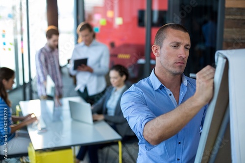 Attentive businessman writing on flip chart