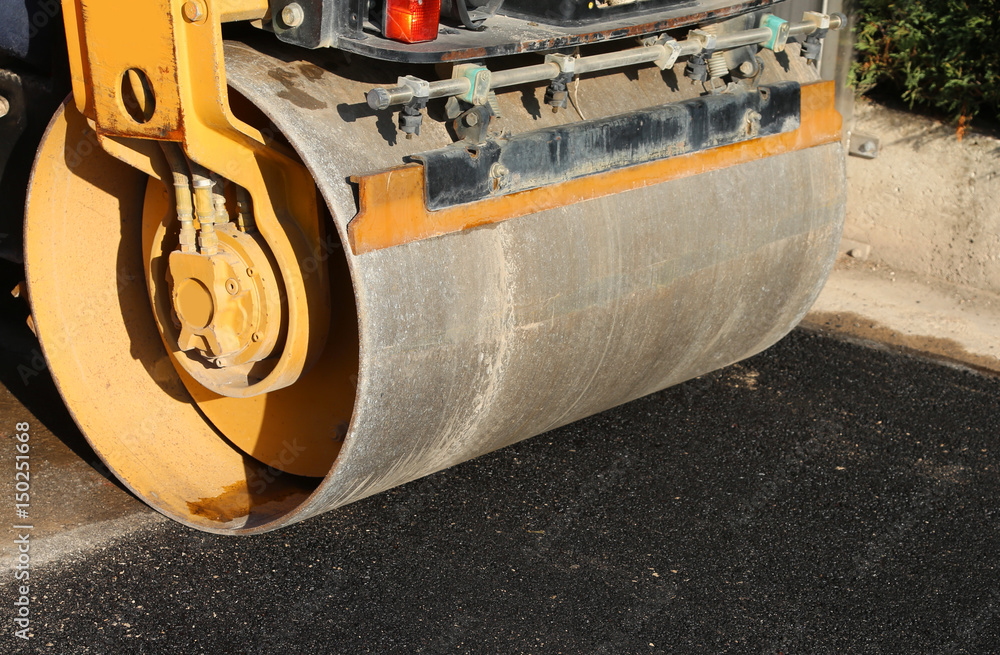 detail of a road roller with the black asphalt of a street