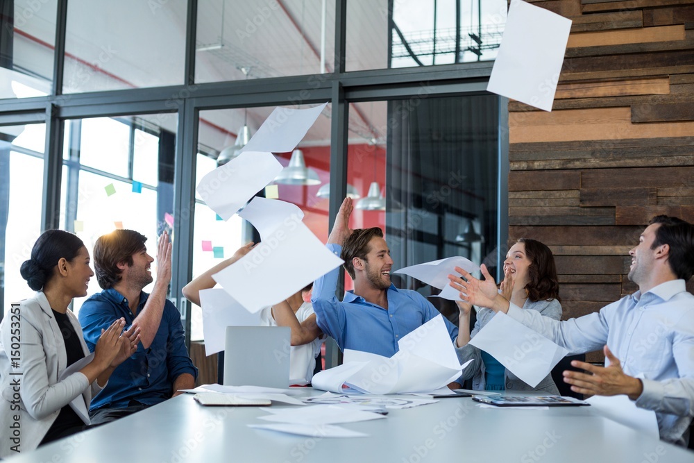 Team of graphic designers throwing documents up in air Team of graphic designers throwing documents up in air