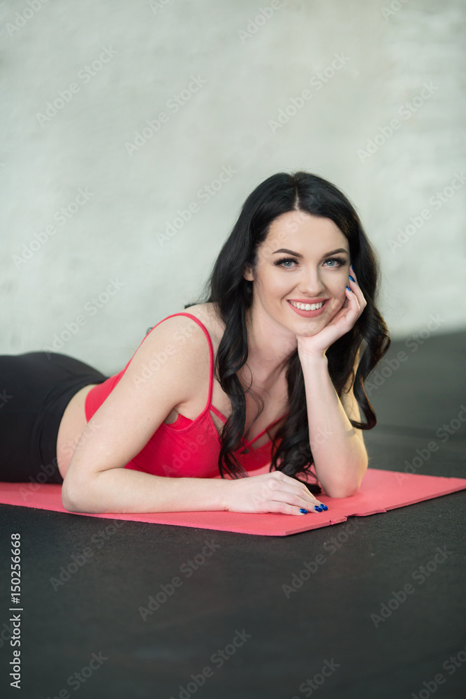 Beautiful girl in a sport suit resting on the mat after the workout Beautiful girl in a sport suit resting on the mat after the workout