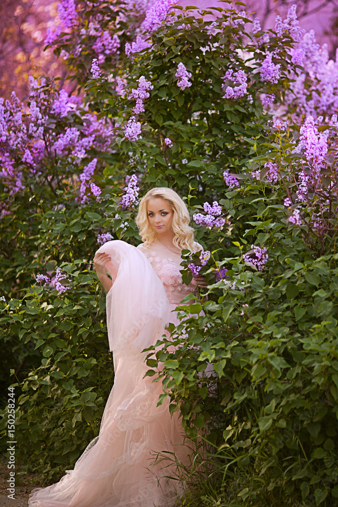 Beautiful woman enjoying lilac garden, young woman with flowers in green park. cheerful teenager walking outdoor. soft light style color.Young girl in beautiful wreath of lilac flowers Beautiful woman enjoying lilac garden, young woman with flowers in green park. cheerful teenager walking outdoor. soft light style color.Young girl in beautiful wreath of lilac flowers